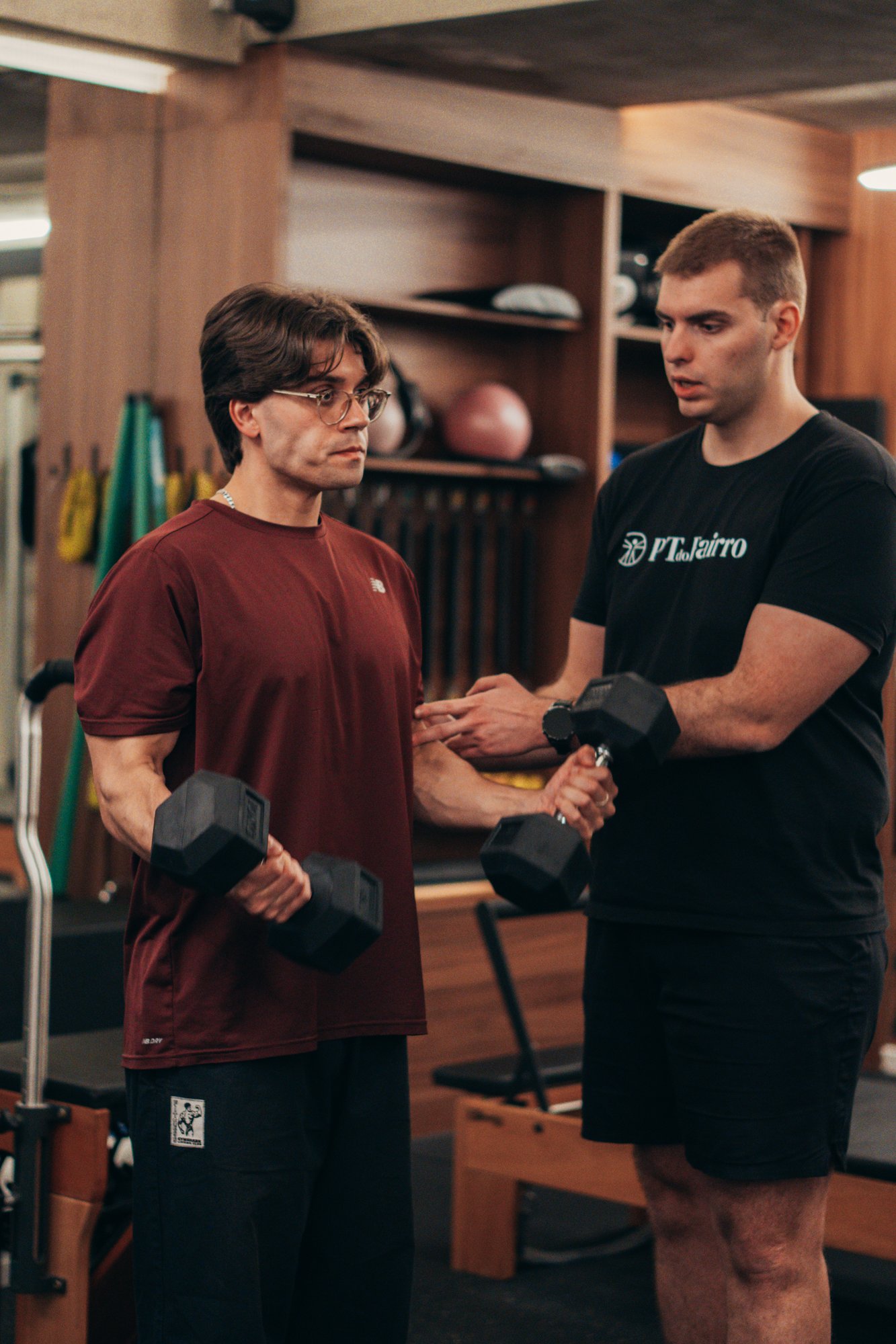 Personal Trainer a acompanhar com proximidade e rigor técnico um exercício de força num estúdio em Lisboa