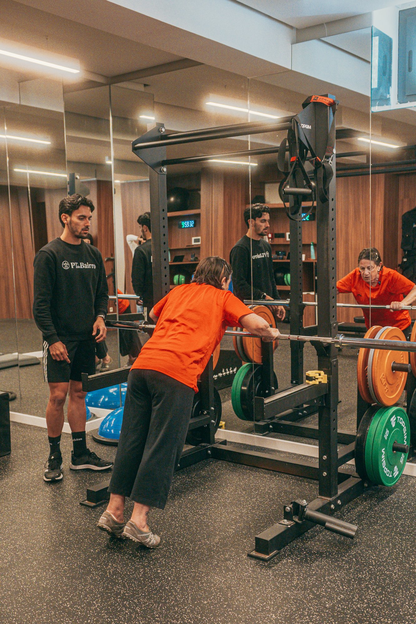Personal Trainer a acompanhar treino de força adaptado para adulto num estúdio em Lisboa