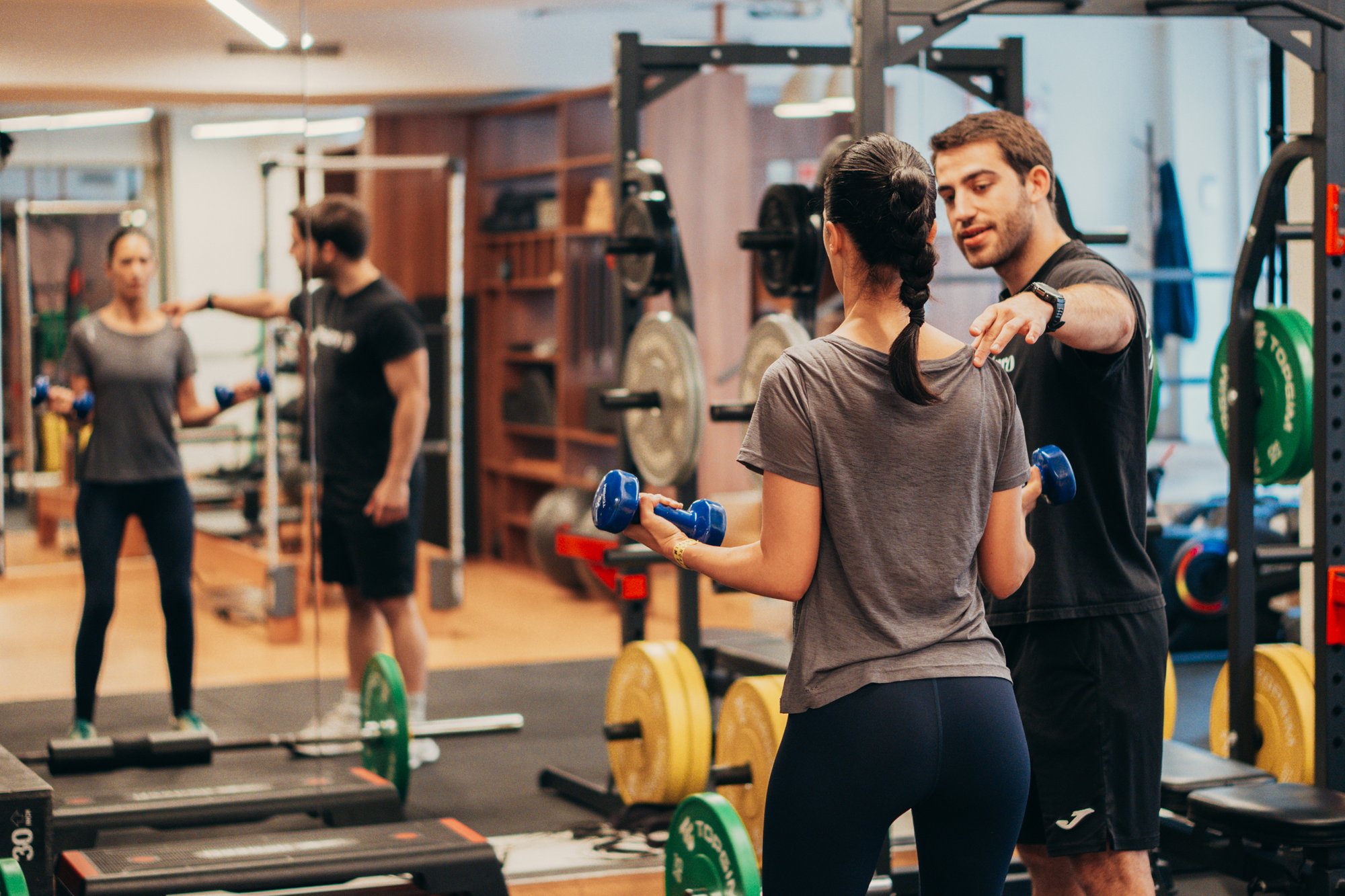 Personal Trainer a corrigir postura de aluno num treino supervisionado em Lisboa